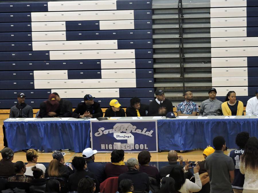 The senior student athletes listen to each others college commitments. The students parents and family members take pictures of them. 