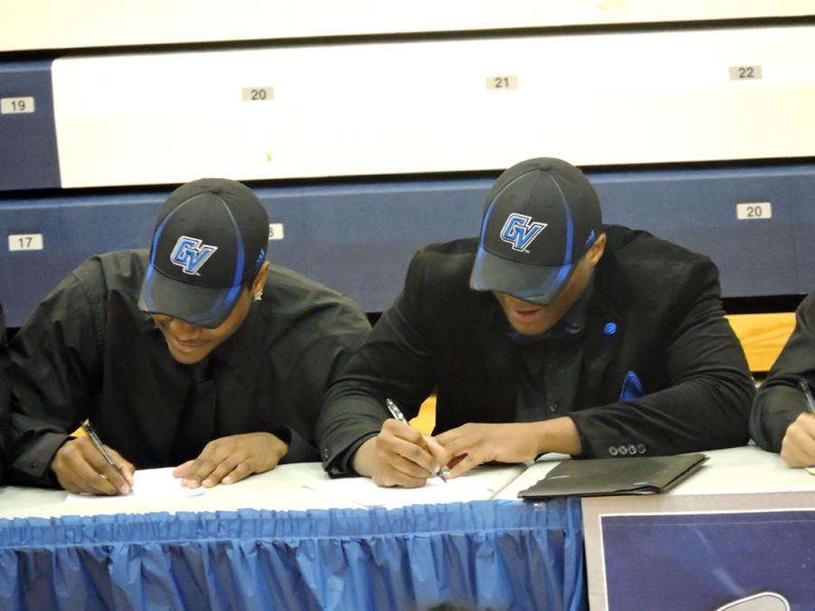Seniors Aaron Cooper (left) and Aaron Turner sign their letters of intent. Cooper and Turner both signed to play football for Grand Valley State University.  Senior Calvin Graves also signed to play football for Grand Valley.