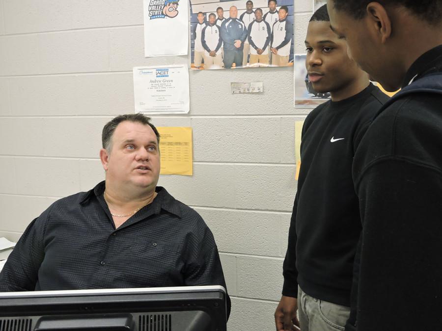 9 to 5: History teacher Andrew Green (seated) confers with juniors Matthew Macon (left) and Kenbon Peete. Green holds three jobs but still finds time to attend Detroit Tigers baseball games. He is a Tigers season ticket holder.