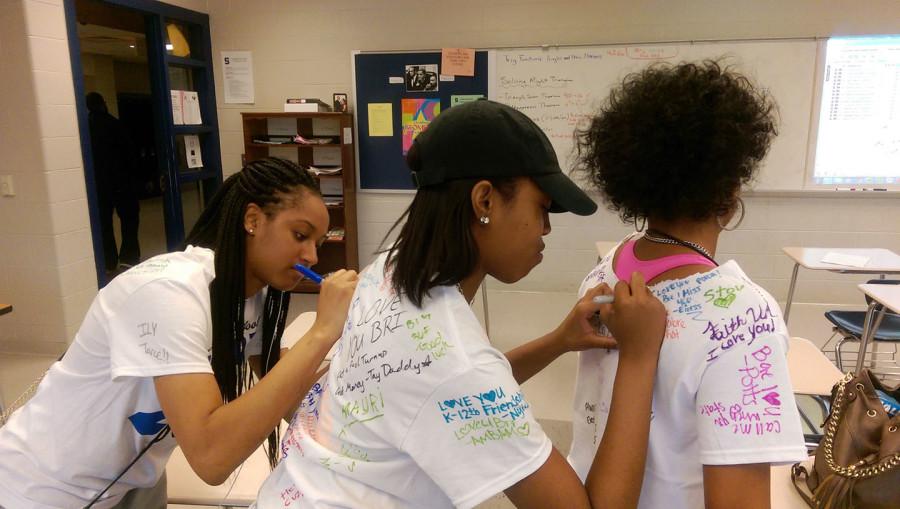 Jabre Wallace, Brianna Rushin, and Rekele Blanding create a t-shirt signing train.