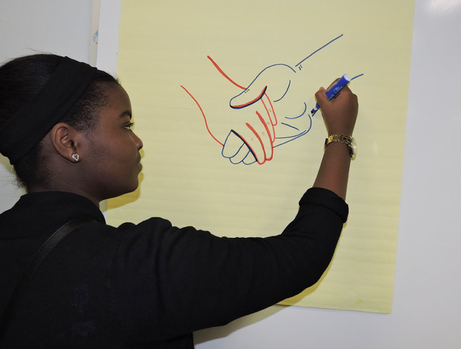 Imagine 2016: Southfield-Lathrup High School junior Amanda Rutledge draws two joined hands, one red, symbolizing Southfield-Lathrup High School, and one blue, symbolizing Southfield High School. The hands are meant to illustrate the upcoming merger of the two high schools in the fall of 2016.