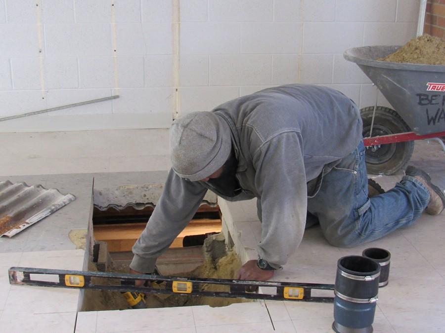 Work Zone: Construction workers break through the floor of room B-115. The former Spanish classroom is converting into a laundry room for the merged schools. 