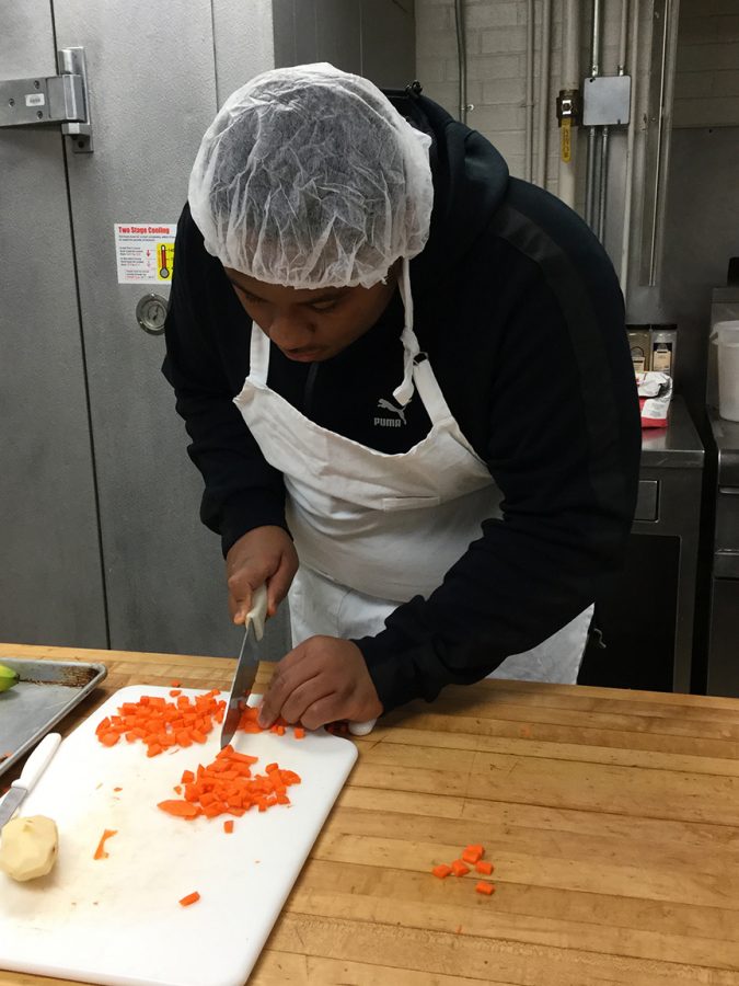 Senior Marcus Rutledge dices carrots for his culinary arts class. Students are required to wear hair nets to keep hair out of the food.